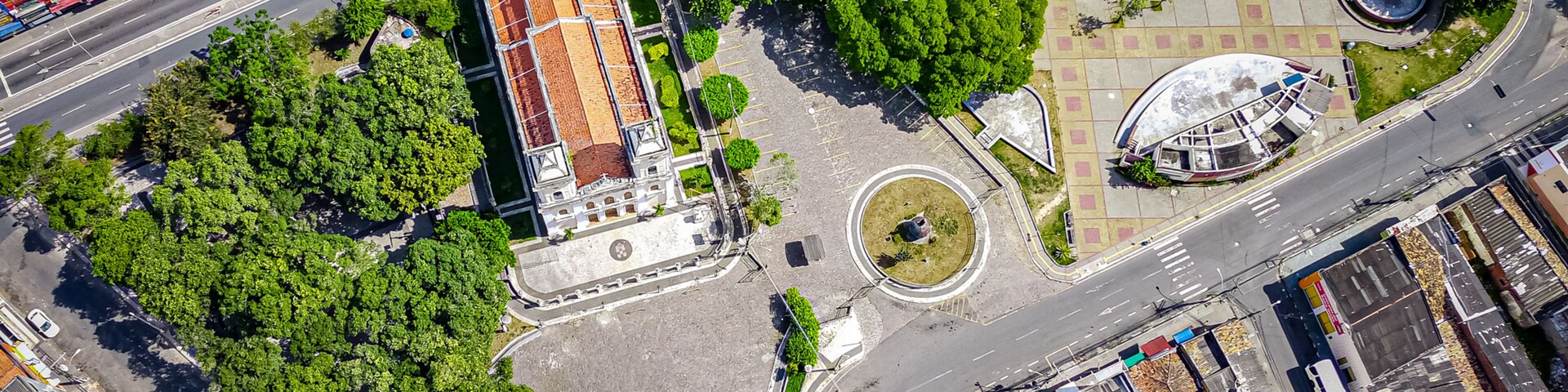 Vista aérea de una intersección urbana con una glorieta, áreas verdes y edificios circundantes.