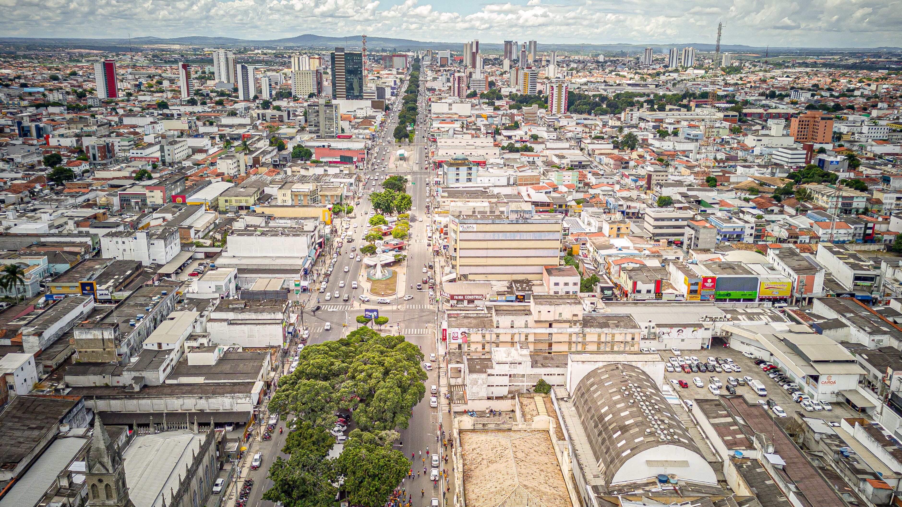 Zona urbana densamente poblada con una mezcla de edificios modernos y antiguos, una vía central y zonas verdes circundantes.
