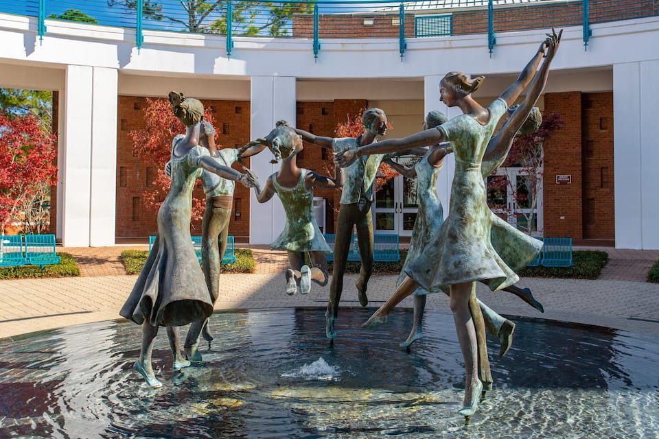 A bronze sculpture of dancers in a fountain.