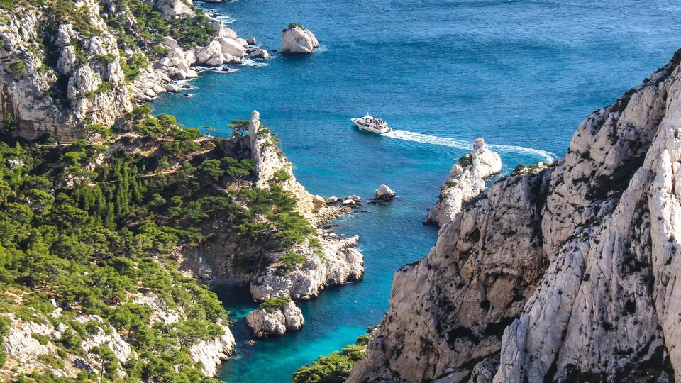 A coastal landscape with rocky cliffs, clear blue waters, and a boat.