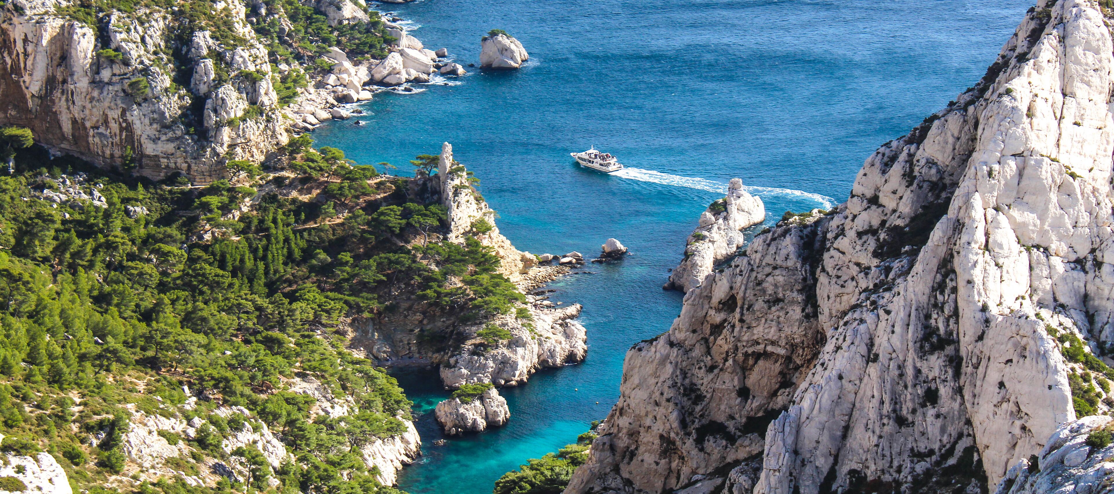 A coastal landscape with rocky cliffs, clear blue waters, and a boat.