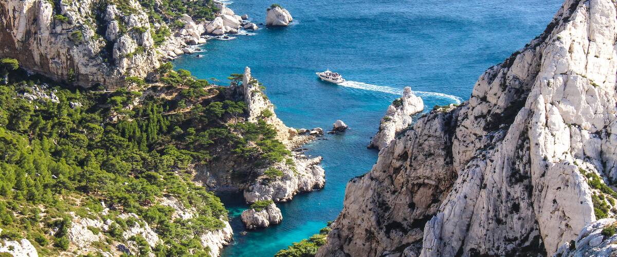 A coastal landscape with rocky cliffs, clear blue waters, and a boat.