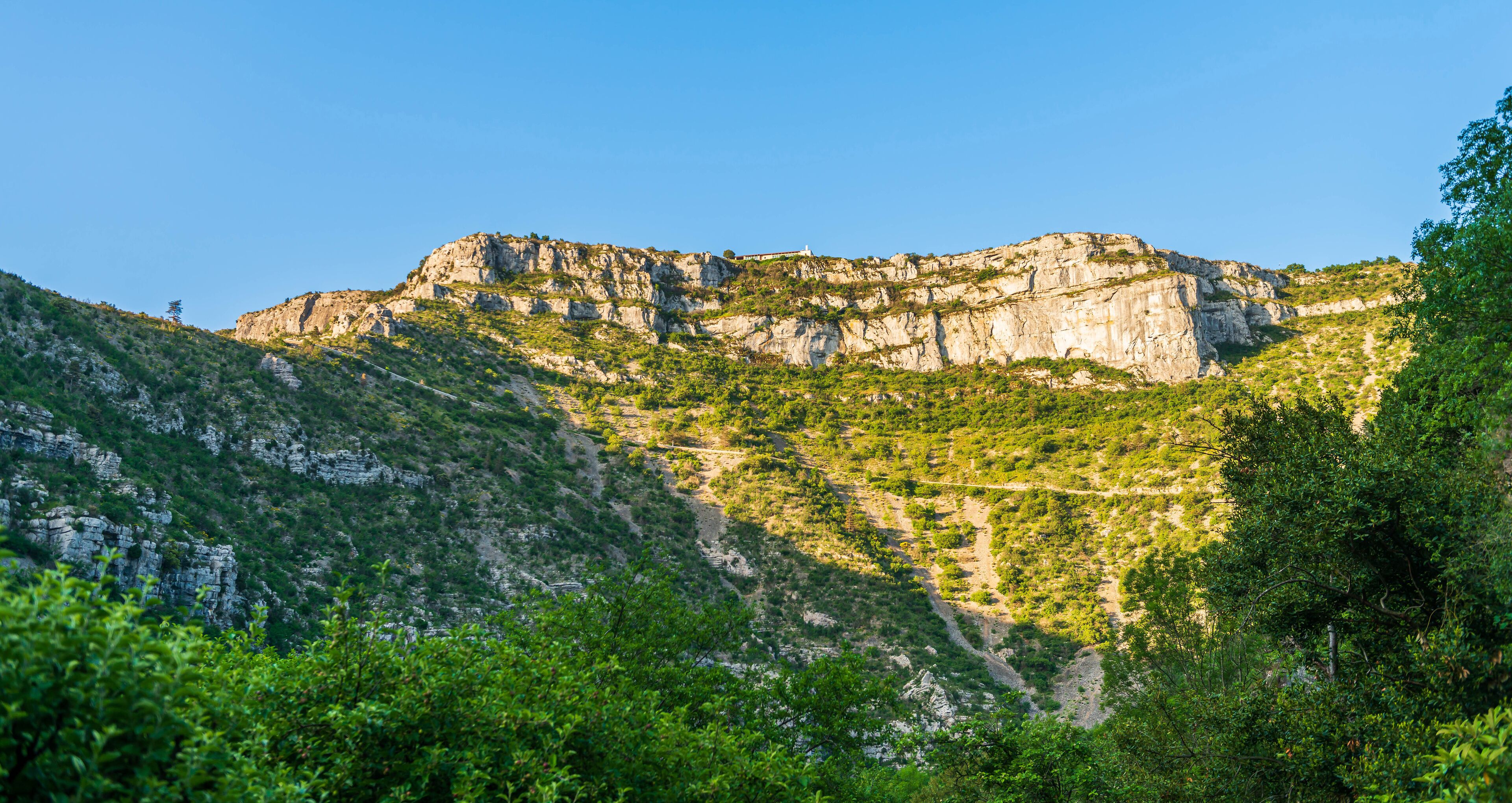 A mountainous landscape with rocky cliffs and dense green vegetation.