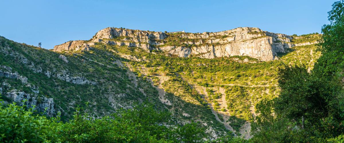 A mountainous landscape with rocky cliffs and dense green vegetation.