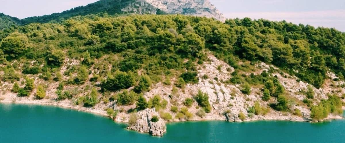 A mountainous landscape with a clear sky, a turquoise lake, and a rocky outcrop in the foreground.