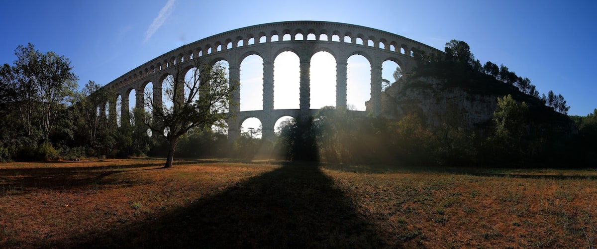 A large stone arch bridge with multiple arches, surrounded by trees and grass.