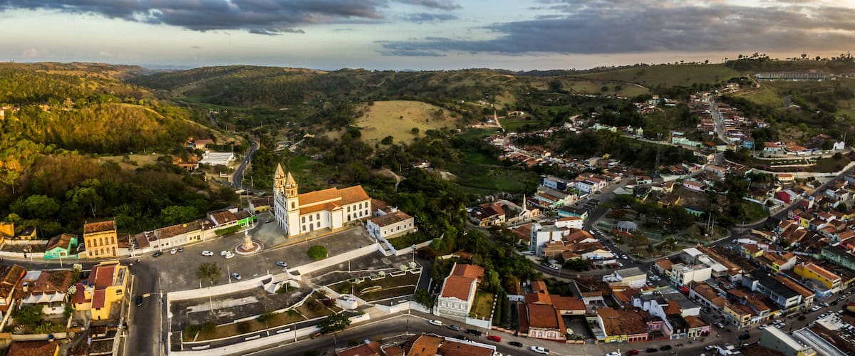 A town with a prominent church, winding roads, and rolling hills in the background.