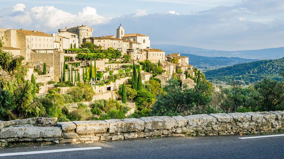 A historic town perched on a hillside with stone walls and lush greenery.