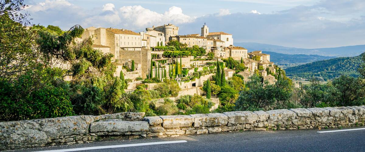 A historic town perched on a hillside with stone walls and lush greenery.