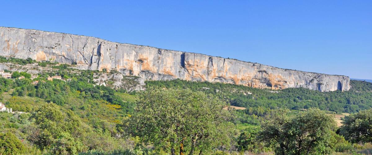 A large limestone cliff with a village at its base.