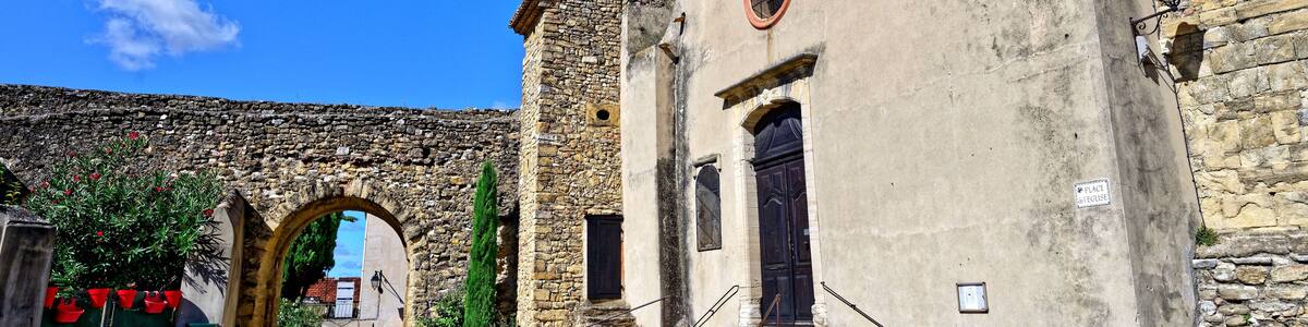 A historic stone building with a bell tower, arched entrance, and steps leading to a door.