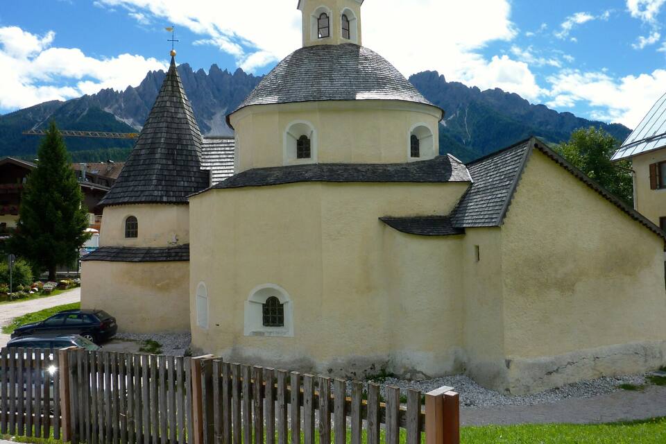 A church with a bell tower and a mountain backdrop.