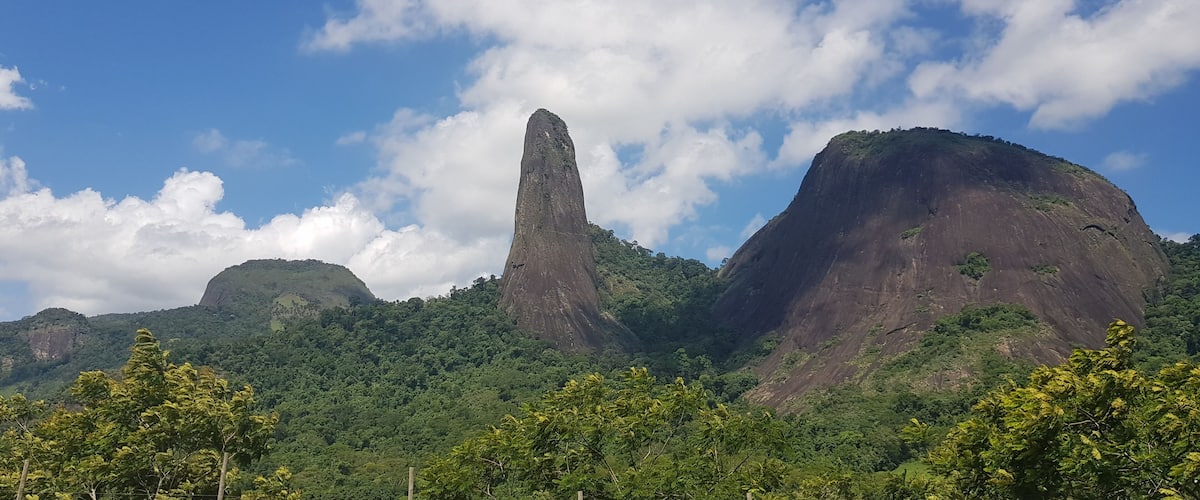 A mountainous landscape with a prominent rock formation and lush greenery.