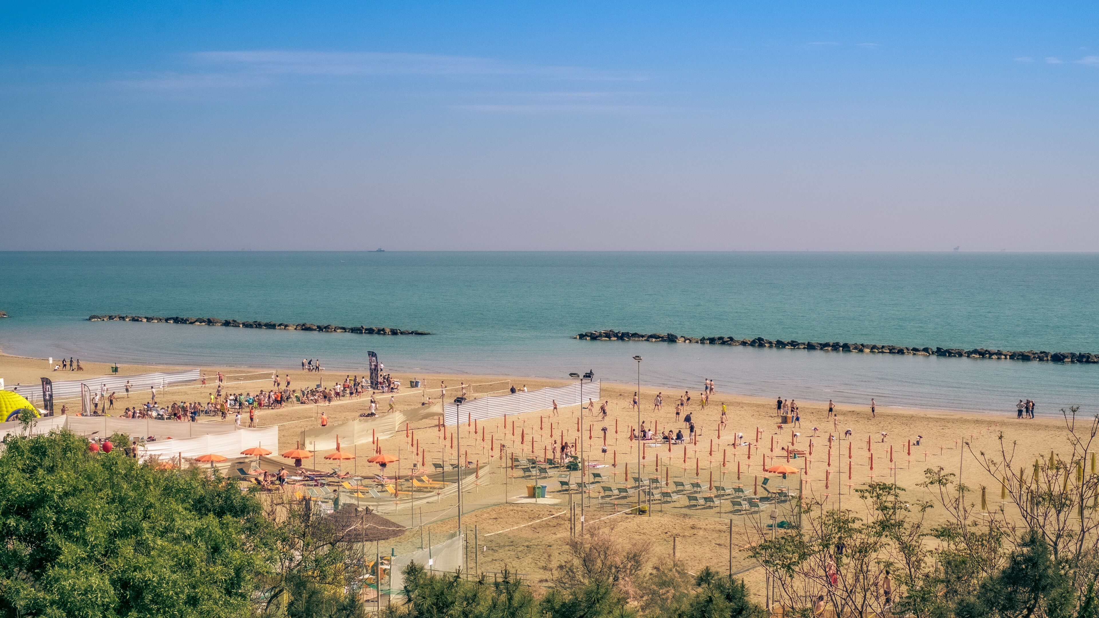 A beach with people, umbrellas, and a clear sky.