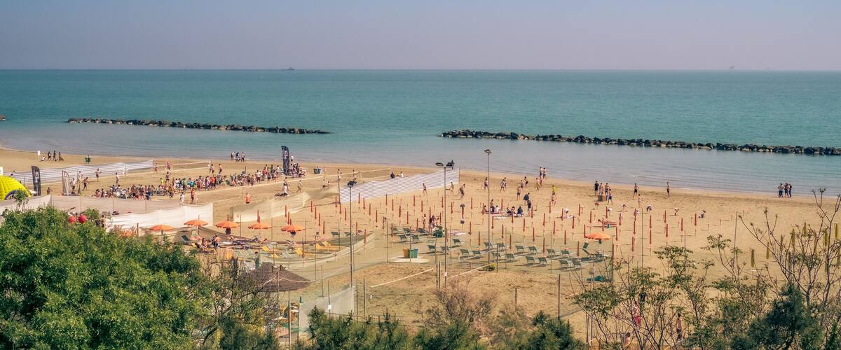 A beach with people, umbrellas, and a clear sky.