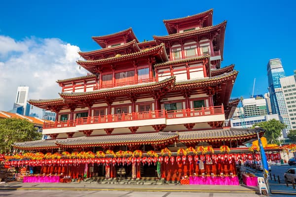 A multi-tiered traditional building with red and white colors, surrounded by modern skyscrapers.