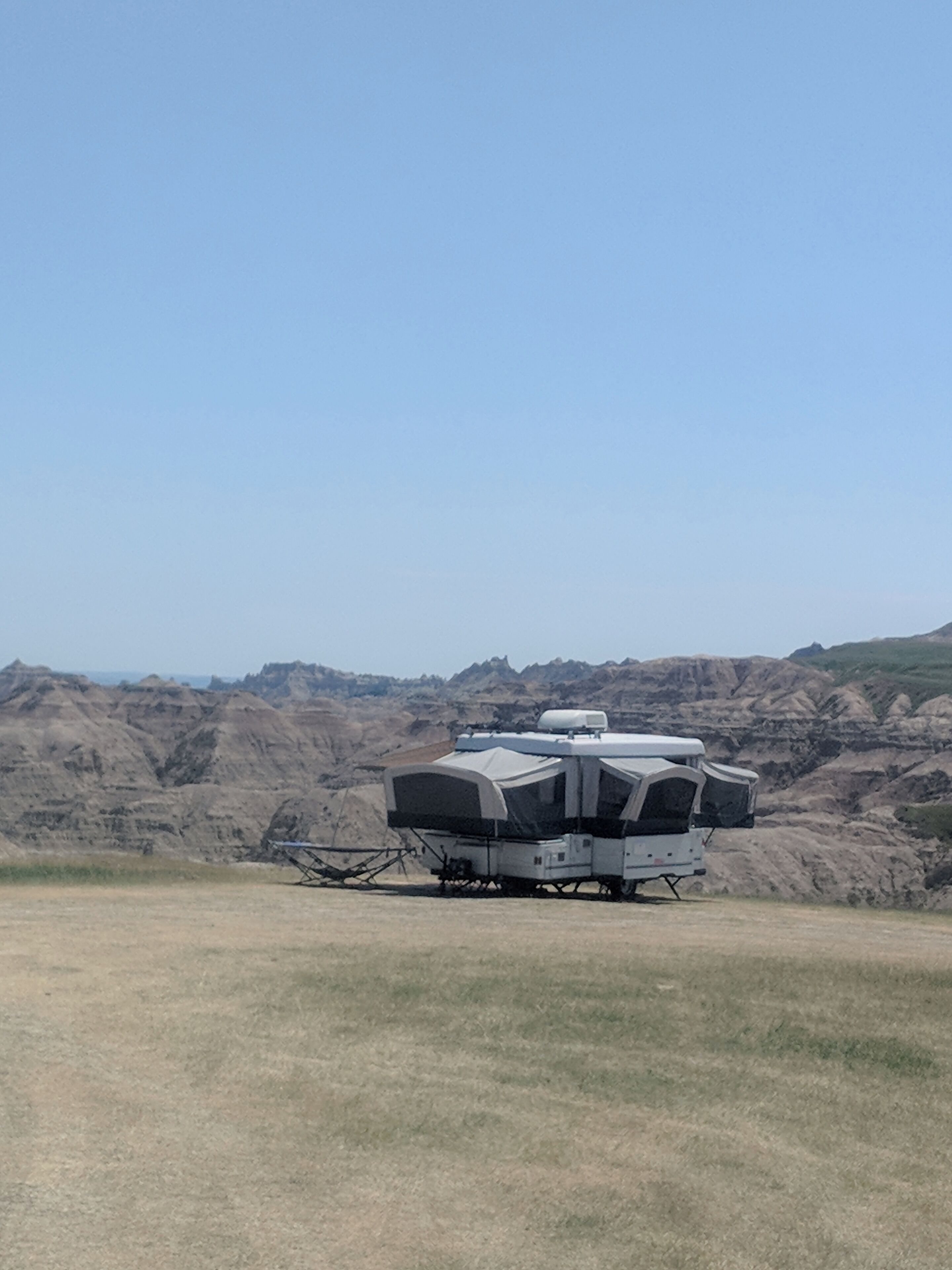 A white RV parked on a grassy field with a mountainous backdrop.