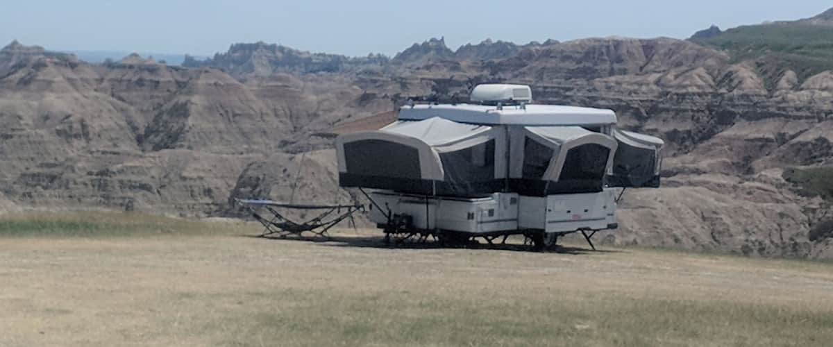 A white RV parked on a grassy field with a mountainous backdrop.