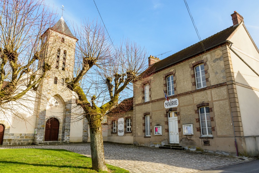 The church square of the small french village of Beauvoir in the department of Seine-et-Marne, 60 kilometers south-east to Paris, with its town hall, church and elementary school in between at sunset.