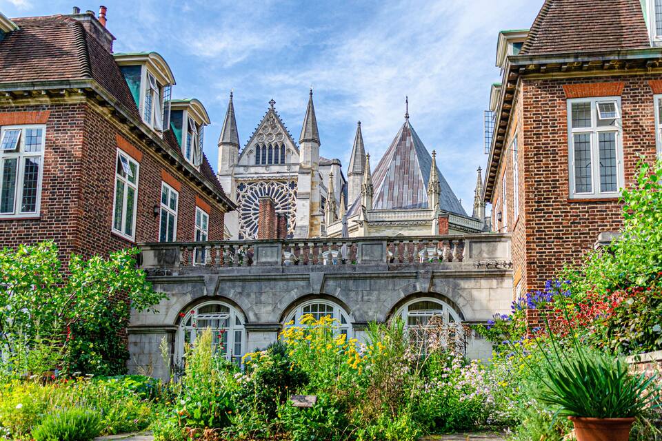 A historic building with intricate architecture and a lush garden in the foreground.