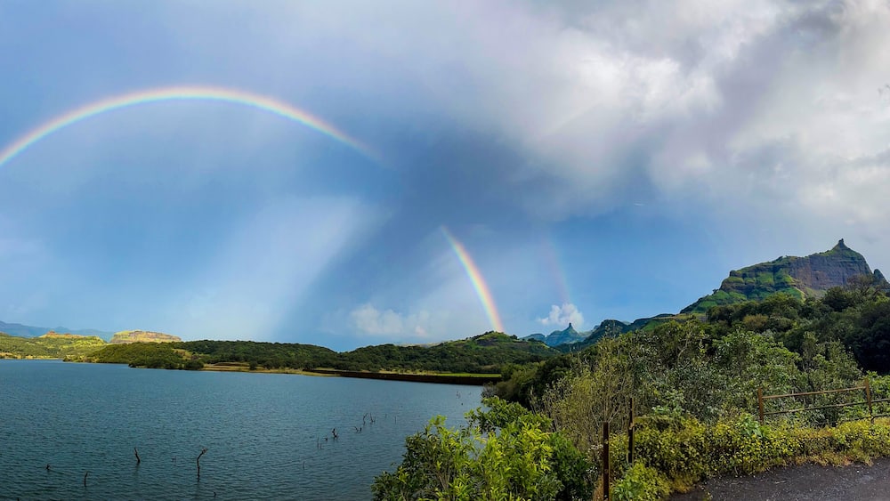 Un lac avec un arc-en-ciel et des montagnes en arrière-plan.