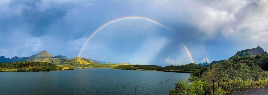 A lake with a rainbow and mountains in the background.