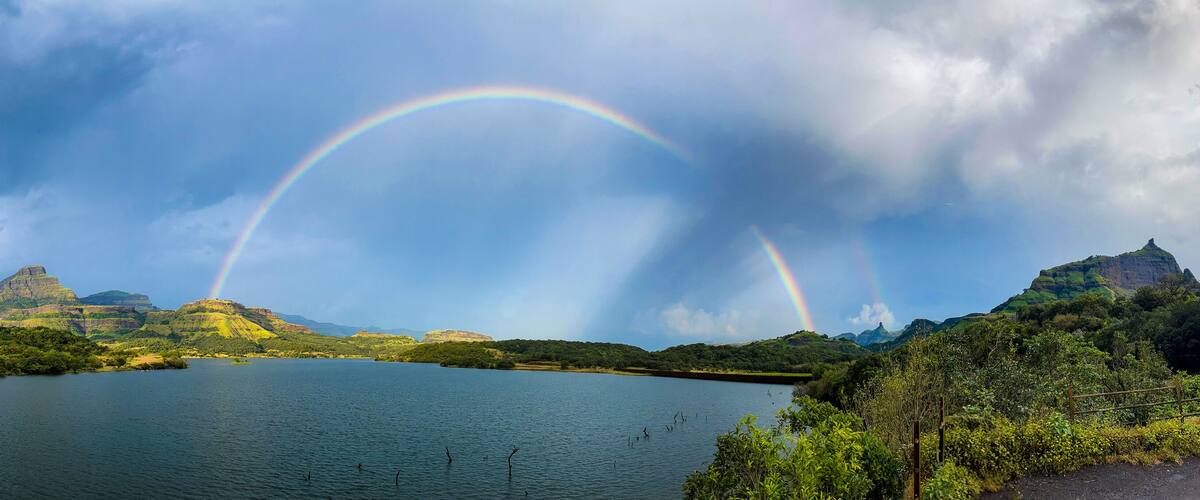 A lake with a rainbow and mountains in the background.