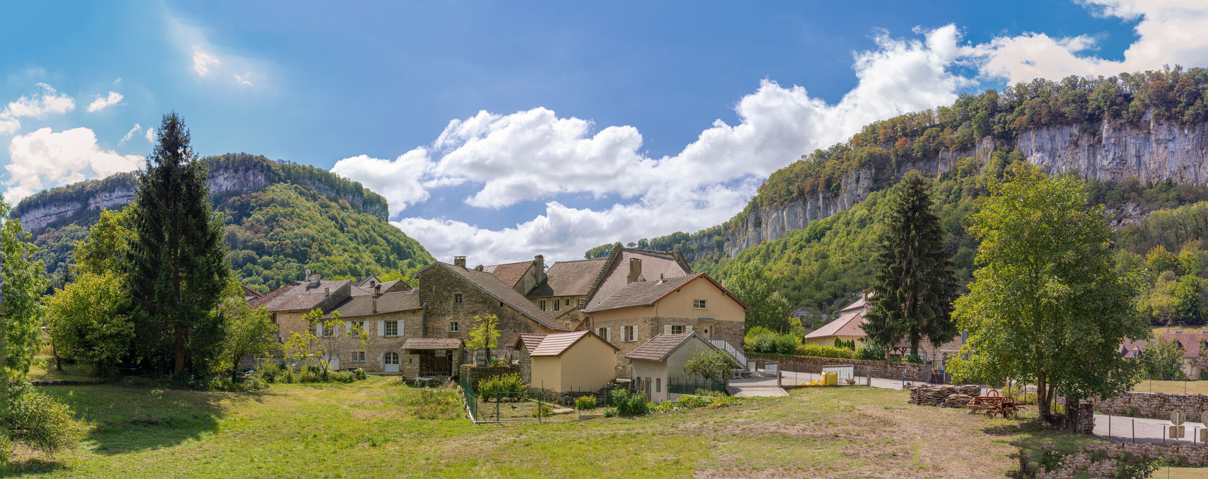 A village with stone houses surrounded by lush greenery and mountains.