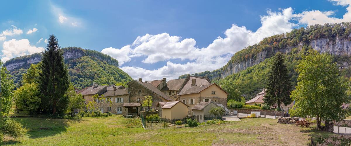 A village with stone houses surrounded by lush greenery and mountains.