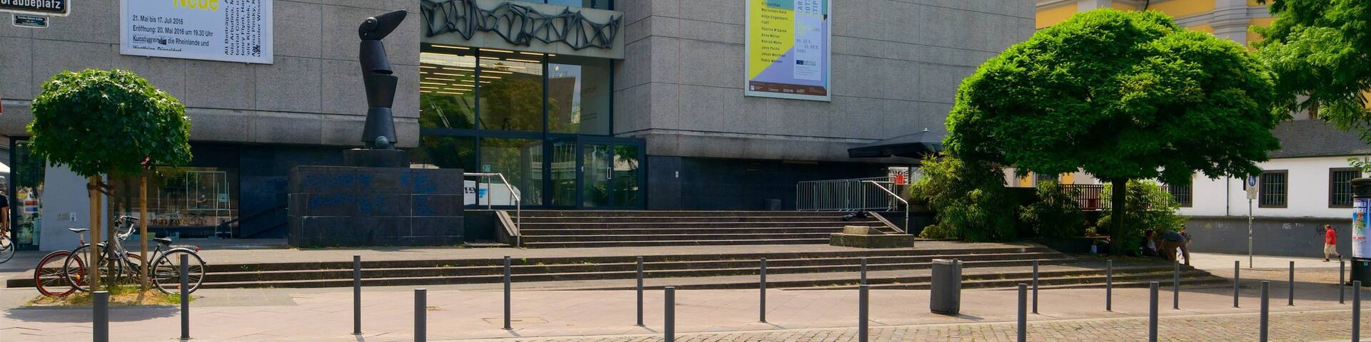A modern building with large banners and a sculpture in front.