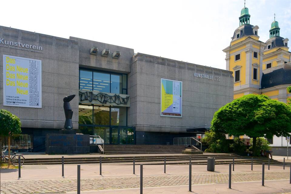 A modern building with large banners and a sculpture in front.