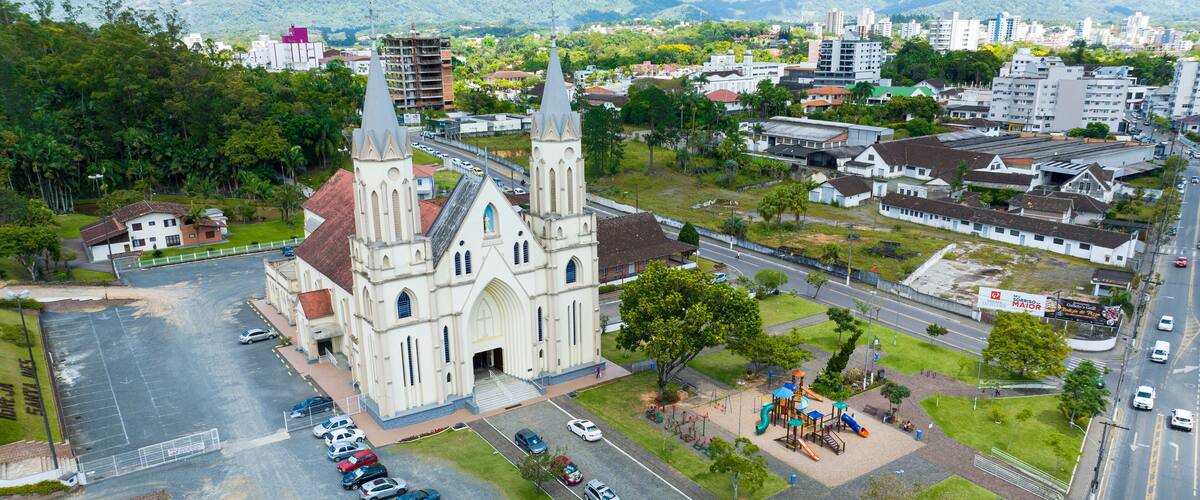 A church with two towers, a parking lot, and a playground.