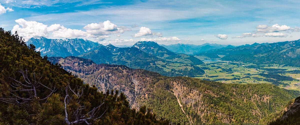 A mountainous landscape with a valley and distant snow-capped peaks.