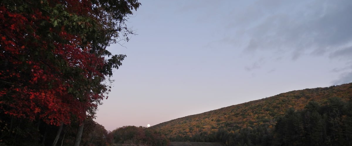 The moon slowly rising on the horizon, as the final light of day dissipates. Tuscarora lake, Tuscarora State Park, Schuylkill County, Barnesville, Pennsylvania, Appalachian Mountains