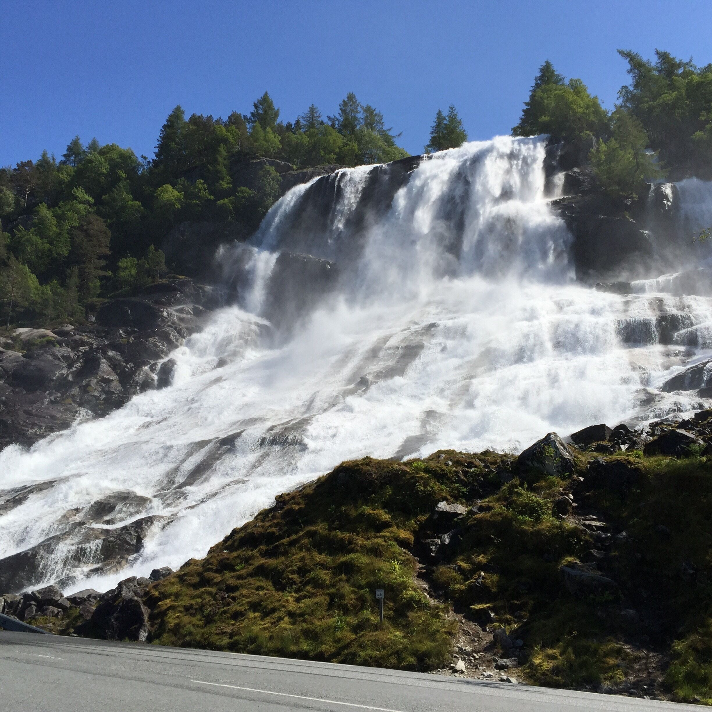 A waterfall cascading down a rocky slope surrounded by dense forest.