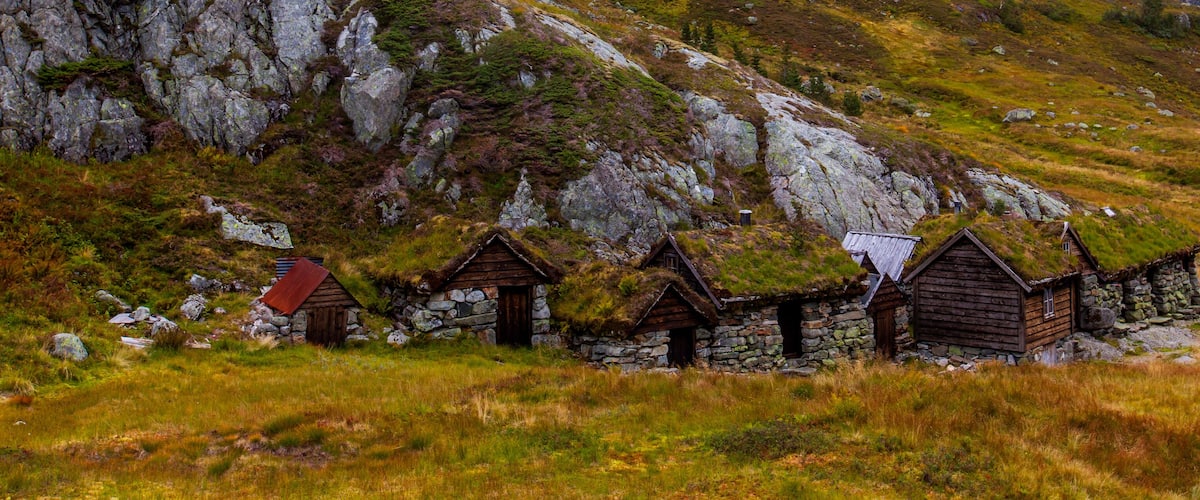 A cluster of traditional stone houses with thatched roofs nestled in a grassy valley.