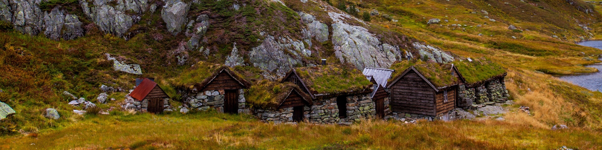 A cluster of traditional stone houses with thatched roofs nestled in a grassy valley.