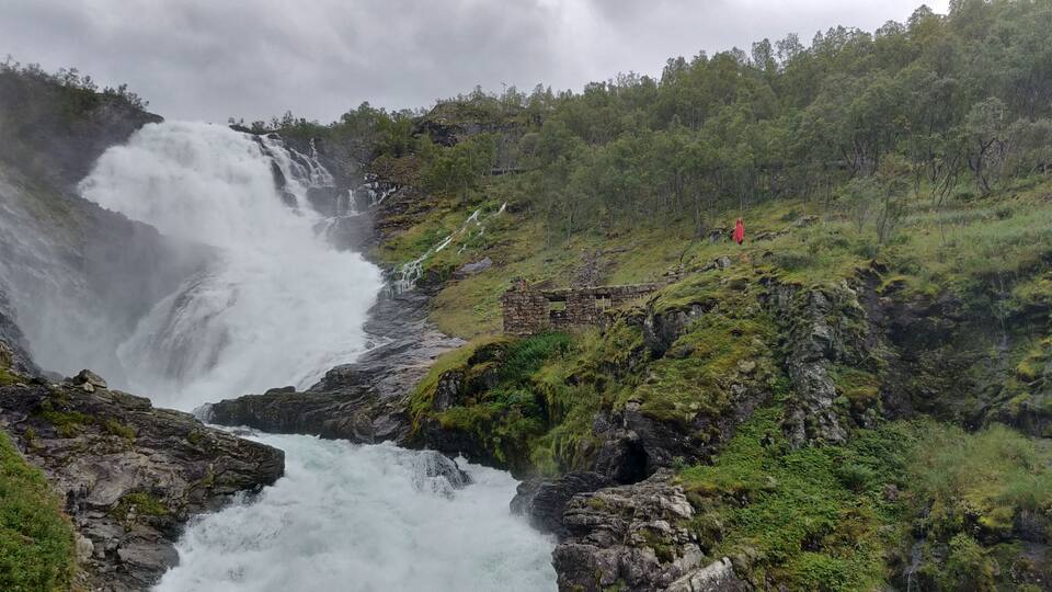 Ett vattenfall som störtar nerför en klippig brant, omgivet av frodig grönska.