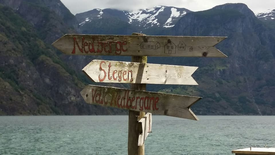 En träskylt med pilar som pekar mot ”Nedre Gjore”, ”Stogen” och ”Vellid/Redbergane”.