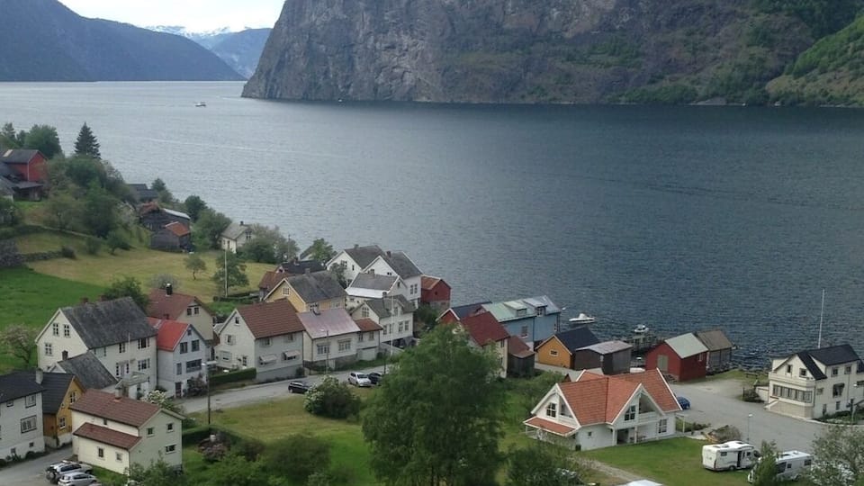 En by vid en sjö med hus och husbilar som står parkerade vid vattnet.