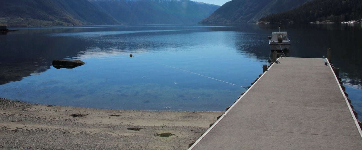 A calm lake surrounded by mountains with a dock extending into the water.