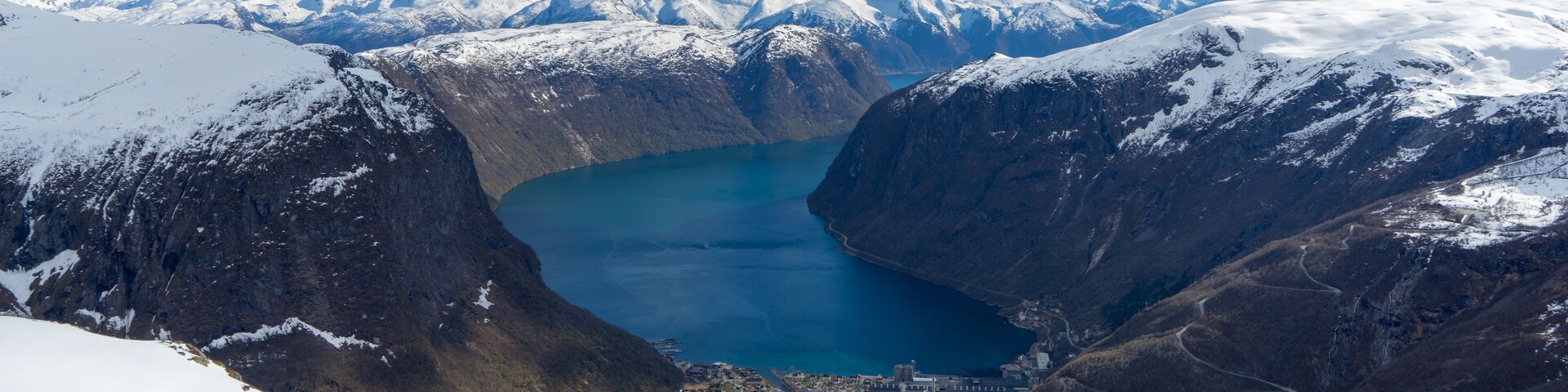 A snow-covered mountain landscape with a lake and a small town at its base.