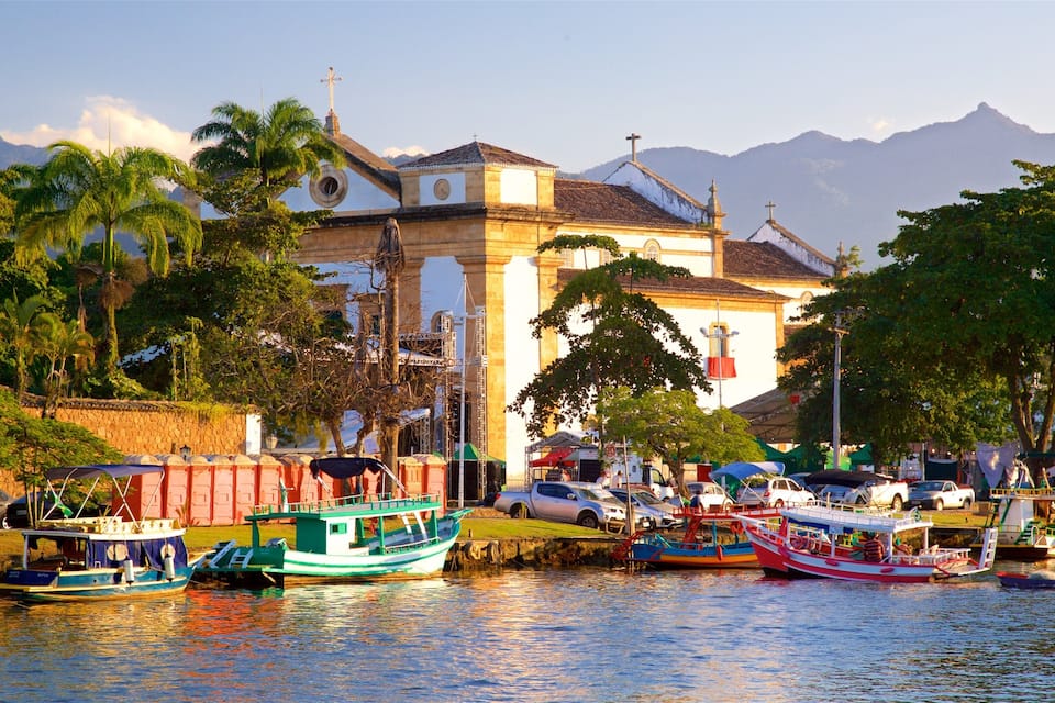 A harbor with boats, a church, and mountains in the background.