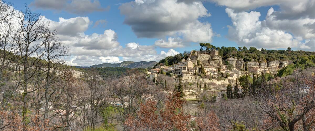 A mountainous village with stone buildings perched on cliffs, surrounded by autumn foliage.