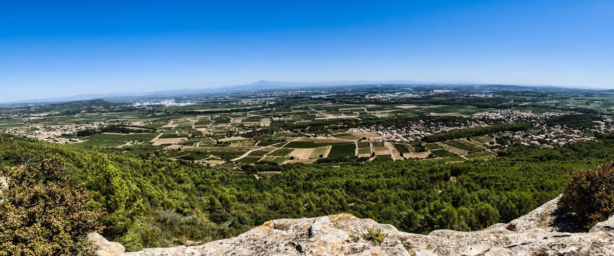 A panoramic view of a valley with agricultural fields, a town, and a mountain in the distance.