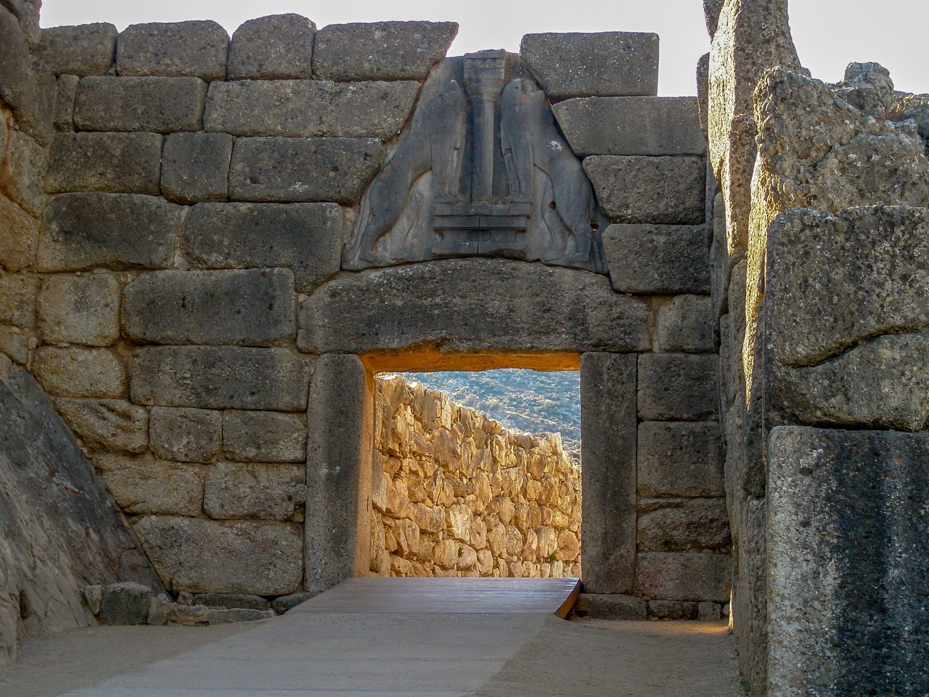 An ancient stone archway with a relief sculpture above it, leading into a rocky landscape.