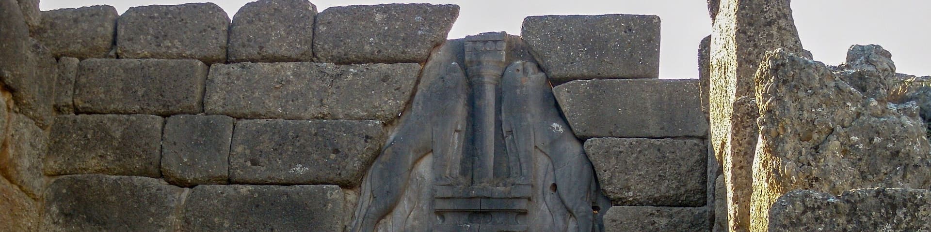 An ancient stone archway with a relief sculpture above it, leading into a rocky landscape.
