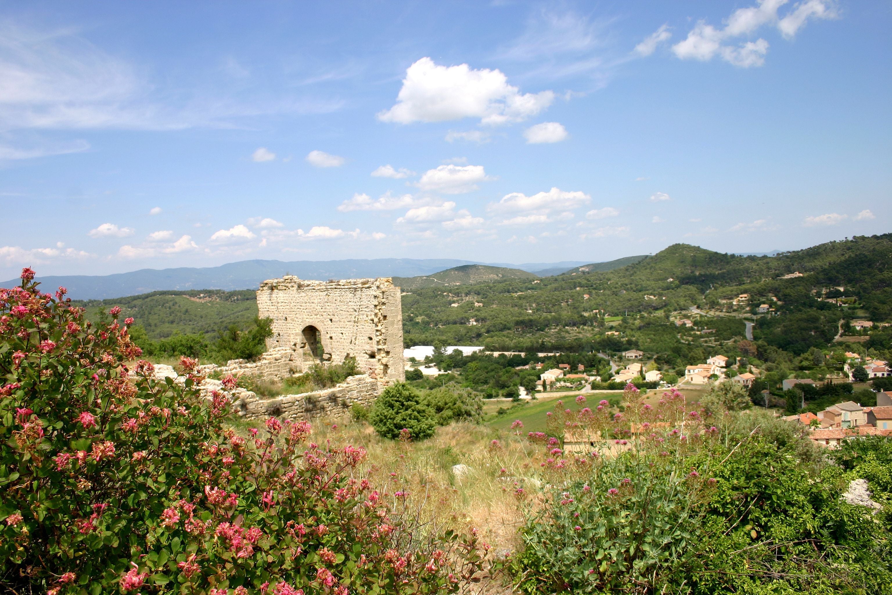 Une tour de pierre se dressant au milieu d’une végétation luxuriante et de collines ondoyantes.