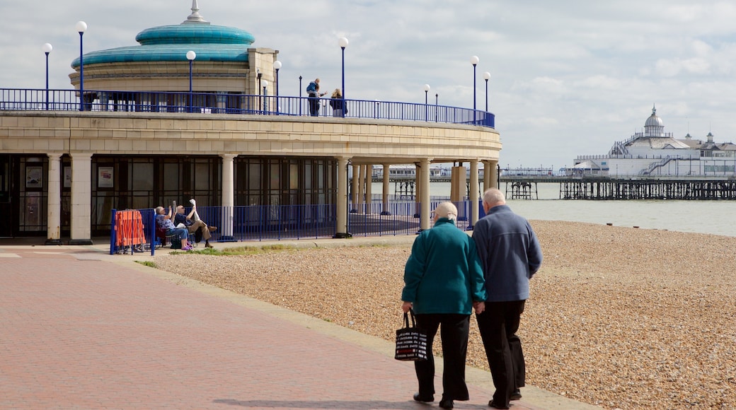 Eastbourne Bandstand que inclui uma praia de pedras assim como um casal
