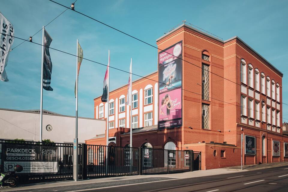 Een theater van rode bakstenen met een groot reclamebord voor een voorstelling.